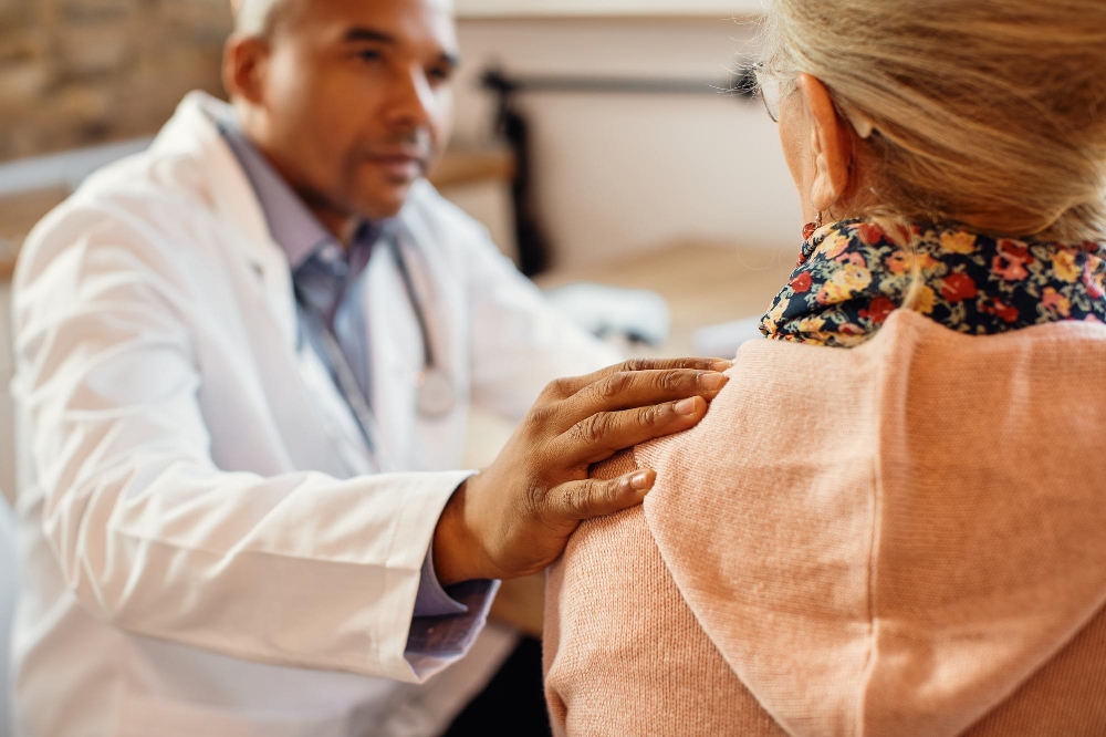 A doctor comforting a senior woman during a home health visit.